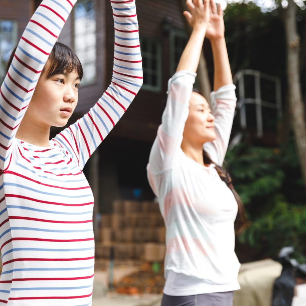 Asian mother and daughter exercising outdoors and practicing tai chi